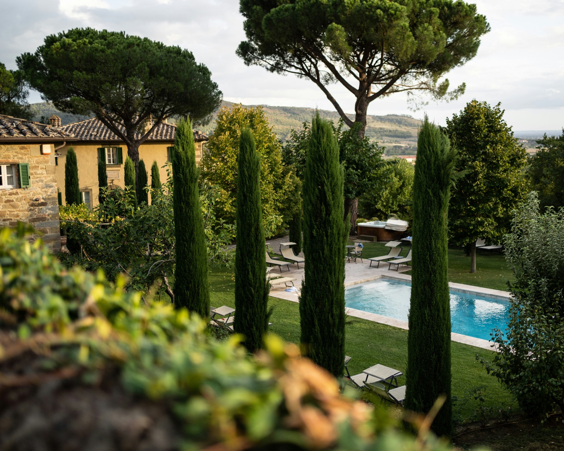 Stone villa with swimming pool and cypress trees overlooking rolling countryside